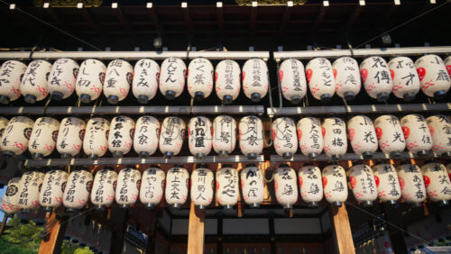 Kyoto, Japan – April 11, 2025: White paper lanterns hanging at the Yasaka Shrine at sunset. Translation: “Names of local businesses and donors” - Starpik Stock