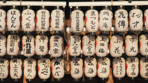 Kyoto, Japan – April 11, 2025: White paper lanterns hanging at the Yasaka Shrine at sunset. Translation: “Names of local businesses and donors” - Starpik Stock