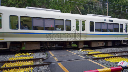 Kyoto, Japan – April 11, 2025: White train passing by the Arashiyama Bamboo Forest. Translation: “Please wait” - Starpik Stock