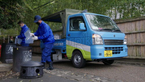 Kyoto, Japan – April 11, 2025: Workers in blue uniforms unloading recycled bottles and changing the trash bags at the Arashiyama Bamboo Forest. Translation: “Kyoto city enviromental policy” - Starpik Stock