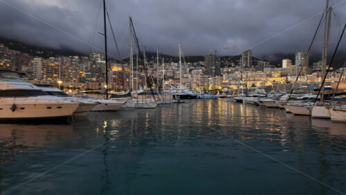 La Condamine, Monaco – July 18, 2025: Packed harbour of yachts against dense hillside apartments under grey clouds - Starpik Stock