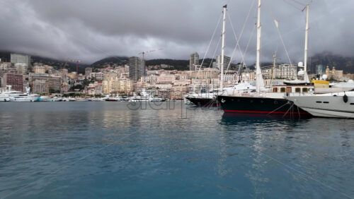 La Condamine, Monaco – July 4, 2025: Row of sleek luxury yachts, docked in Port Hercules with the Monaco cityscape and misty hills in the background - Starpik Stock