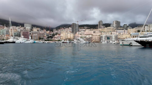 La Condamine, Monaco – July 4, 2025: Row of sleek luxury yachts, docked in Port Hercules with the Monaco cityscape and misty hills in the background - Starpik Stock