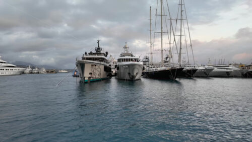 La Condamine, Monaco – July 4, 2025: Row of sleek luxury yachts, docked in Port Hercules with the Monaco cityscape and misty hills in the background - Starpik Stock