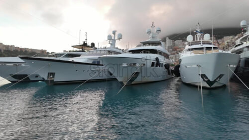 La Condamine, Monaco – July 4, 2025: Row of sleek luxury yachts, docked in Port Hercules with the Monaco cityscape and misty hills in the background - Starpik Stock