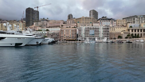 La Condamine, Monaco – July 4, 2025: Row of sleek luxury yachts, docked in Port Hercules with the Monaco cityscape and misty hills in the background - Starpik Stock