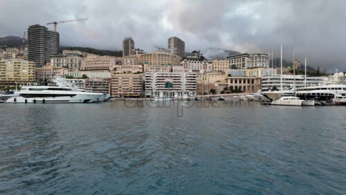 La Condamine, Monaco – July 4, 2025: Row of sleek luxury yachts, docked in Port Hercules with the Monaco cityscape and misty hills in the background - Starpik Stock