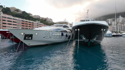 La Condamine, Monaco – July 4, 2025: Row of sleek luxury yachts, docked in Port Hercules with the Monaco cityscape and misty hills in the background - Starpik Stock