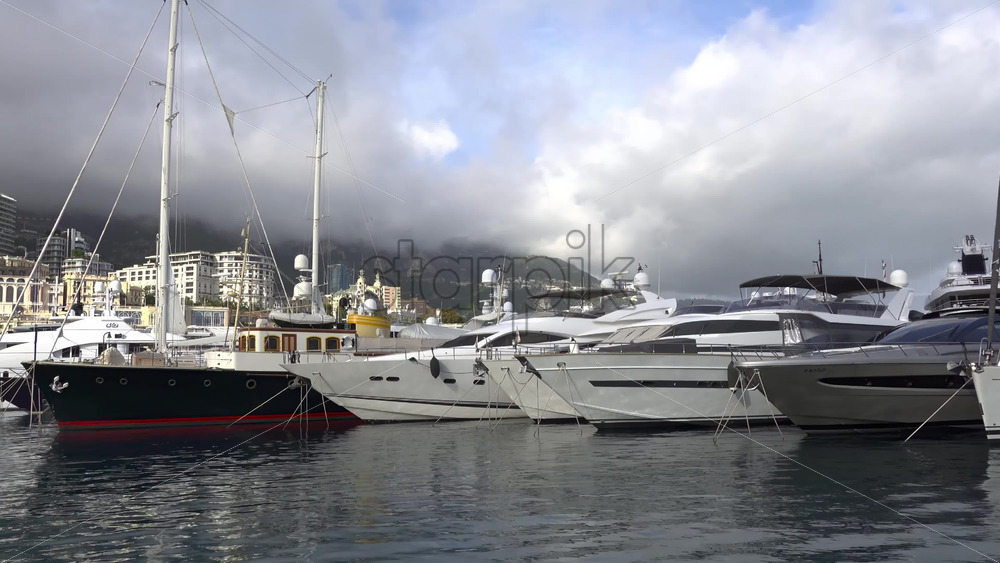 La Condamine, Monaco – July 4, 2025: Row of sleek luxury yachts, docked in Port Hercules with the Monaco cityscape and misty hills in the background - Starpik Stock