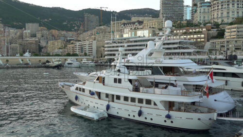 La Condamine, Monaco – July 8, 2025: Boats docked in Port Hercule with buildings on the background in the evening - Starpik Stock
