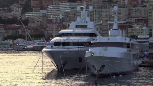 La Condamine, Monaco – July 8, 2025: Boats docked in Port Hercule with buildings on the background in the evening - Starpik Stock