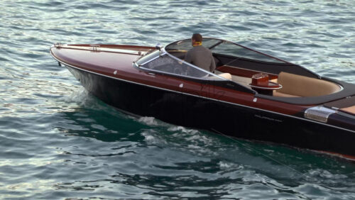 La Condamine, Monaco – July 8, 2025: Wooden speedboat gliding across calm harbour water at dusk - Starpik Stock