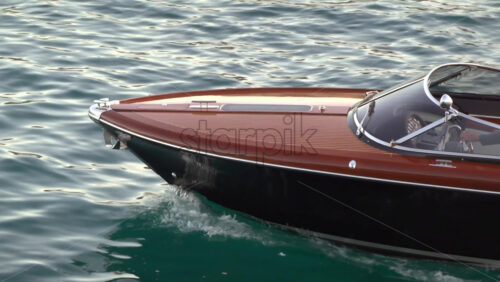 La Condamine, Monaco – July 8, 2025: Wooden speedboat gliding across calm harbour water at dusk - Starpik Stock