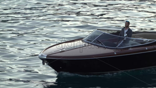 La Condamine, Monaco – July 8, 2025: Wooden speedboat gliding across calm harbour water at dusk - Starpik Stock