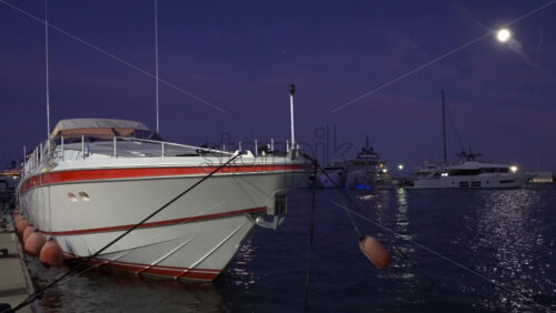 Large motor yacht docked in the harbour with multiple boats on the background in the evening - Starpik Stock