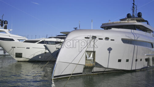 Large yachts docked in the Cannes harbour in daylight in France - Starpik Stock