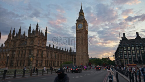 London, England – May 11, 2025: Big Ben and the Houses of Parliament seen from Westminster Bridge in the evening, with vehicles and pedestrians passing by - Starpik Stock