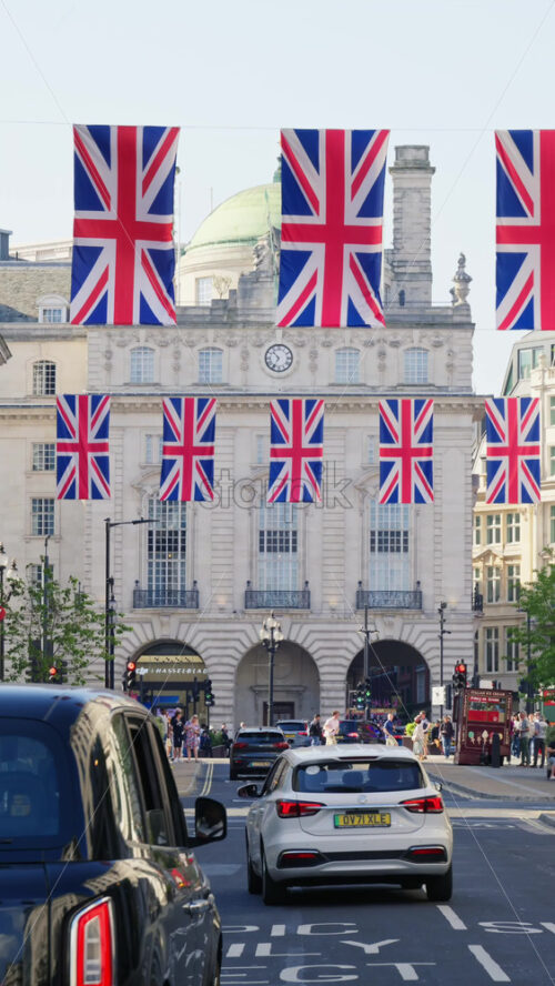 London, England – May 11, 2025: Cars moving under multiple flags of the United Kingdom hanging proudly above Regent street. Vertical - Starpik Stock