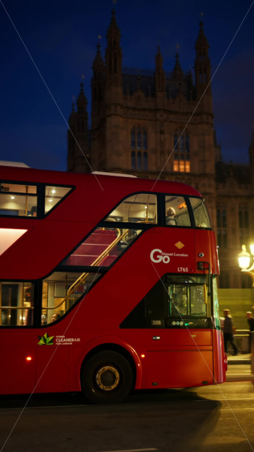 London, England – May 11, 2025: Close up of a red double decker moving near the Big Ben in the evening. Vertical - Starpik Stock