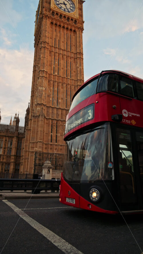 London, England – May 11, 2025: Close up of a red double decker moving near the Big Ben in the evening. Vertical - Starpik Stock