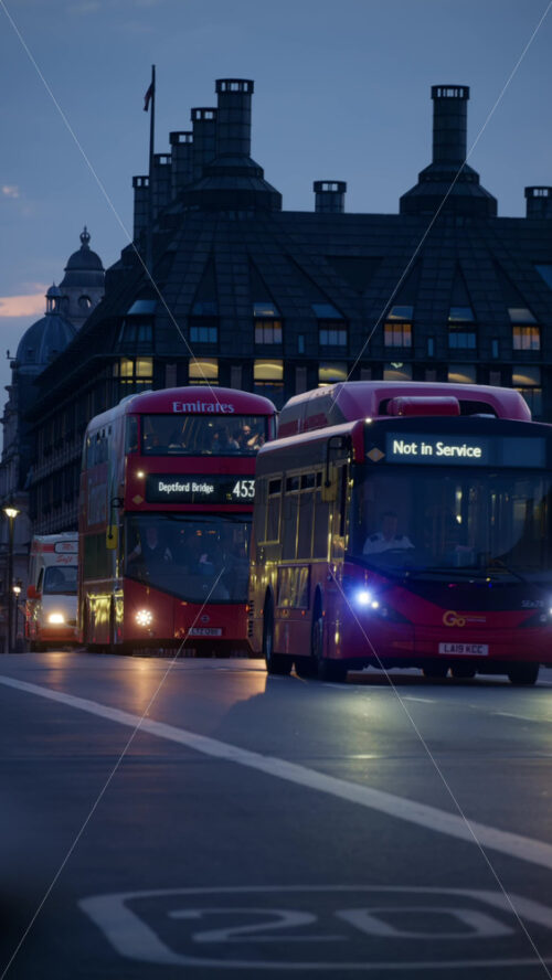 London, England – May 11, 2025: Double decker busses and cars moving on the street near Westminster in the evening. Vertical - Starpik Stock