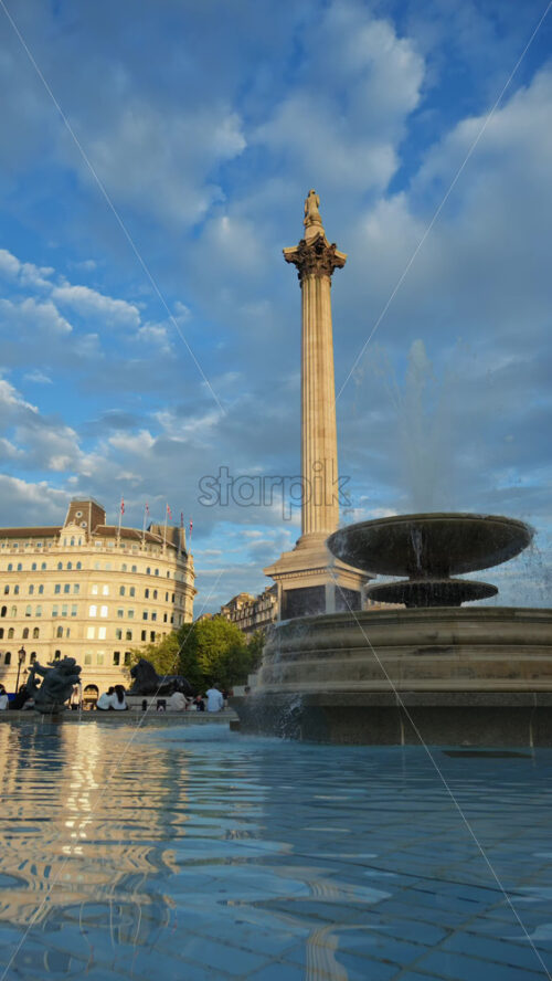 London, England – May 11, 2025: Trafalgar square featuring a large water fountain and people enjoying the sunny day. Vertical - Starpik Stock