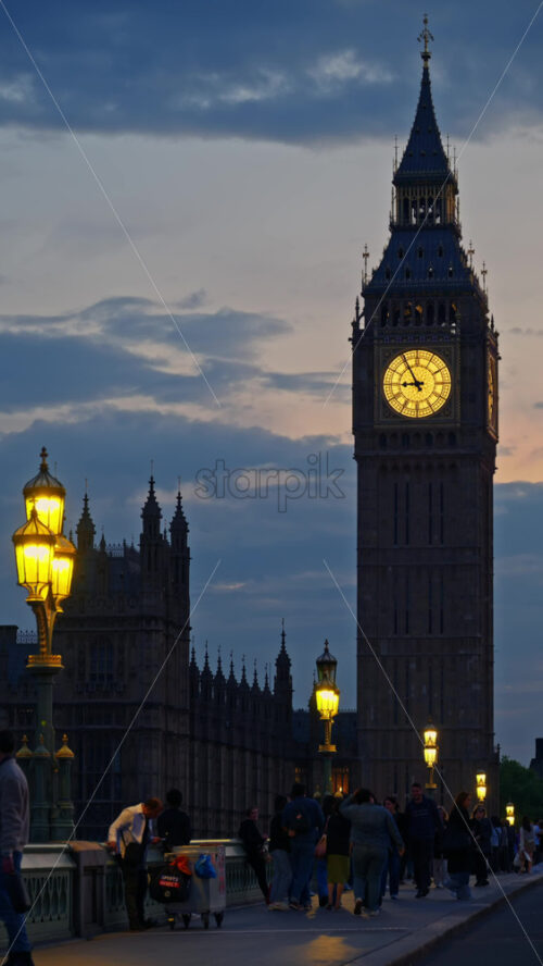 London, England – May 11, 2025: View of Big Ben illuminated at dusk with people walking in font of it. Vertical - Starpik Stock