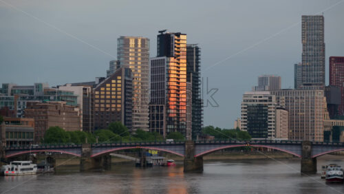 London, England – May 11, 2025: View of the cityscape with high-rise buildings reflecting golden light during sunset across the River Thames - Starpik Stock