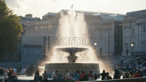 London, England – May 11, 2025: Water fountain in the Trafalgar Square surrounded by people enjoying a sunny evening - Starpik Stock