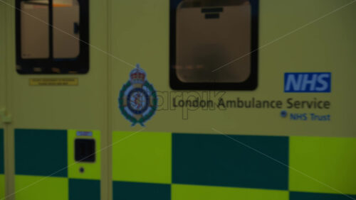 London, England – May 11, 2025: Yellow ambulance with flashing lights rushing through city streets at night - Starpik Stock