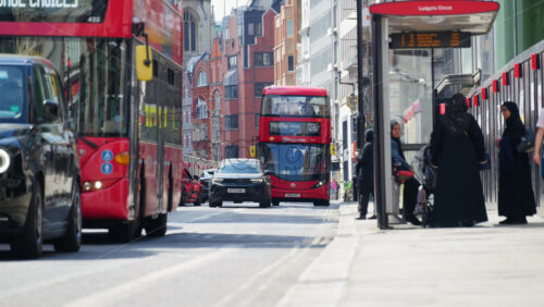 London, England – May 12, 2025: Busy Faringdon street with red buses, pedestrians at a bus stop, and traditional city buildings - Starpik Stock