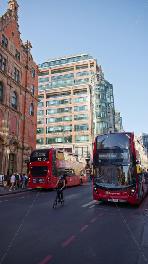 London, England – May 12, 2025: Busy Liverpool street with red buses, pedestrians and traditional city buildings. Vertical - Starpik Stock