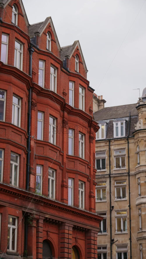 London, England – May 12, 2025: Calm street view of red brick Victorian-style buildings typical of London’s historic neighbourhoods. Vertical - Starpik Stock