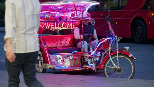 London, England – May 12, 2025: Colourful pedicab decorated with Union Jack flags and neon lights waiting for passengers on a central street in the evening - Starpik Stock