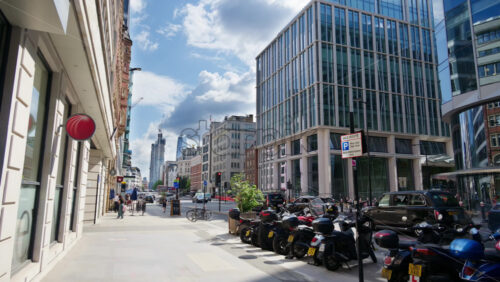 London, England – May 12, 2025: Faringdon Street view with parked scooters, modern glass office buildings, and busy life - Starpik Stock