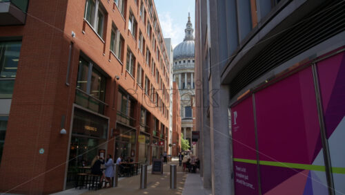 London, England – May 12, 2025: Framed view of St. Paul’s Cathedral dome between two modern brick buildings - Starpik Stock