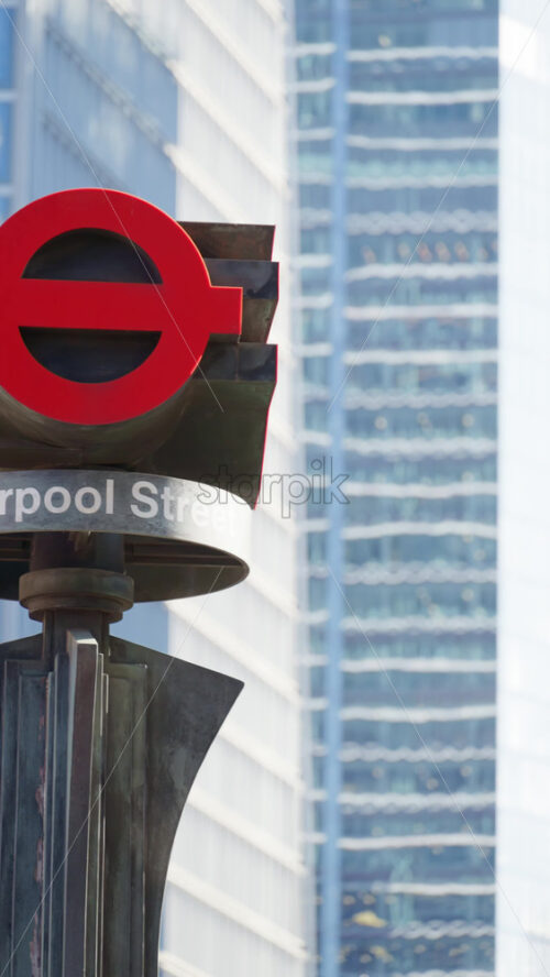 London, England – May 12, 2025: Red London Underground sign at Liverpool Street station, framed by modern city buildings. Vertical - Starpik Stock