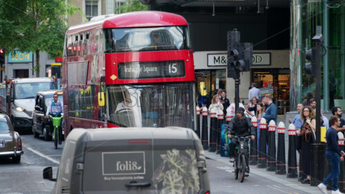 London, England – May 12, 2025: Red double-decker bus on Cannon Street headed to Trafalgar Square navigating through the city traffic as people cross the road - Starpik Stock