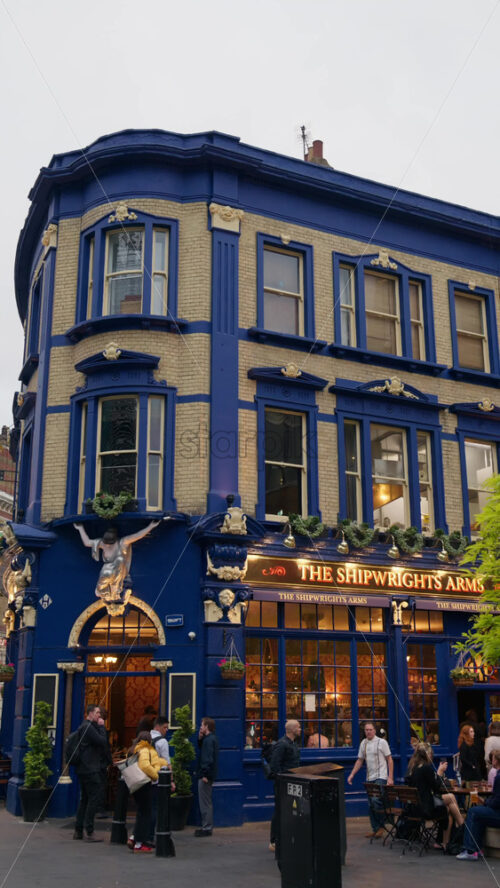 London, England – May 12, 2025: The Shipwrights Arms, a classic blue London pub with people socializing outside. Vertical - Starpik Stock