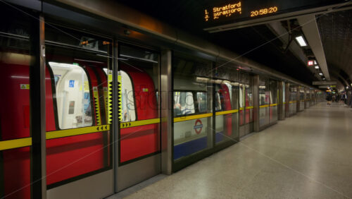 London, England – May 12, 2025: The doors of a red and white Underground train closing inside a modern tube station during the evening rush hour - Starpik Stock