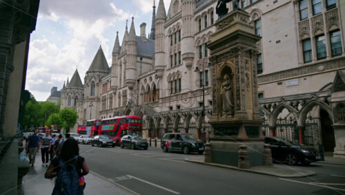 London, England – May 12, 2025: Time lapse of a busy street scene outside the Royal Courts of Justice, with tourists walking and iconic red buses passing by on a cloudy afternoon - Starpik Stock
