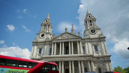 London, England – May 12, 2025: Time lapse of the St. Paul’s Cathedral with red buses and pedestrians along a busy street. Moving clouds and blue sky - Starpik Stock