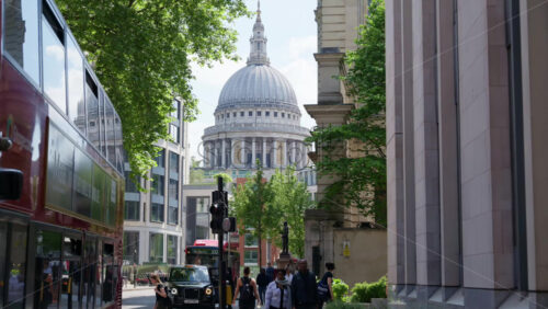 London, England – May 12, 2025: View of St. Paul’s Cathedral with red buses and pedestrians along a busy street - Starpik Stock