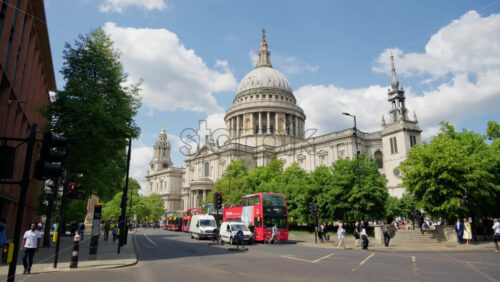 London, England – May 12, 2025: View of St. Paul’s Cathedral with red buses and pedestrians along a busy street - Starpik Stock