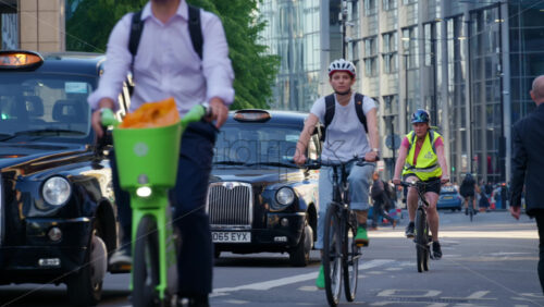 London, England – May 13, 2025: A group of cyclists commuting through the city near Liverpool Station on a sunny morning with glass buildings in the background - Starpik Stock