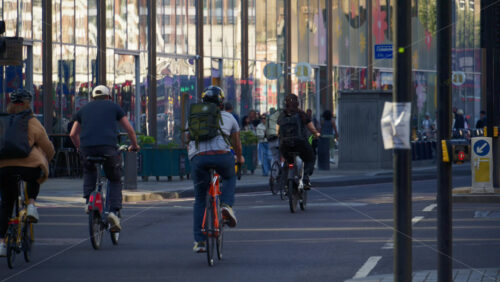 London, England – May 13, 2025: A group of cyclists commuting through the city on a sunny morning with glass buildings in the background - Starpik Stock