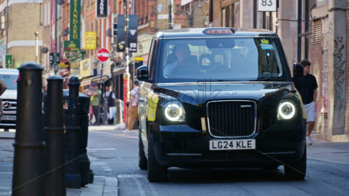 London, England – May 13, 2025: Busy view of Brick Lane filled with pedestrians, shops, and colourful storefronts on a sunny day - Starpik Stock
