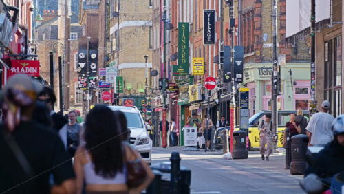 London, England – May 13, 2025: Busy view of Brick Lane filled with pedestrians, shops, and colourful storefronts on a sunny day - Starpik Stock