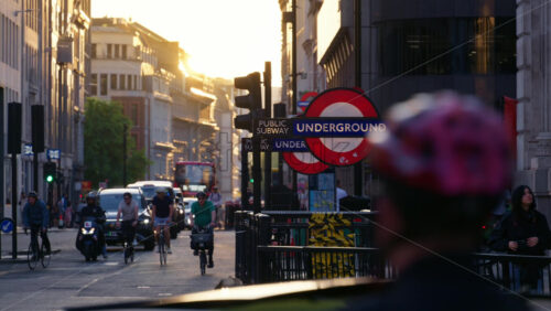 London, England – May 13, 2025: Cyclists and vehicles navigating the streets with an Underground sign in view, capturing urban life in the evening - Starpik Stock
