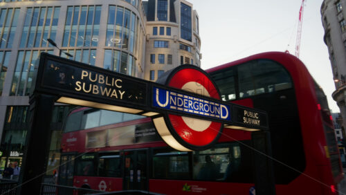 London, England – May 13, 2025: Double-decker bus navigating the streets with an Underground sign in view, capturing urban life in the evening - Starpik Stock